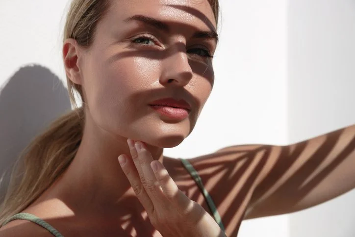 Woman posing in sunlight with shadows across her face