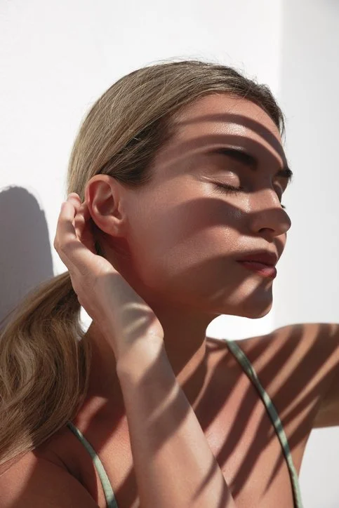 Woman with luminous skin in patterned sunlight